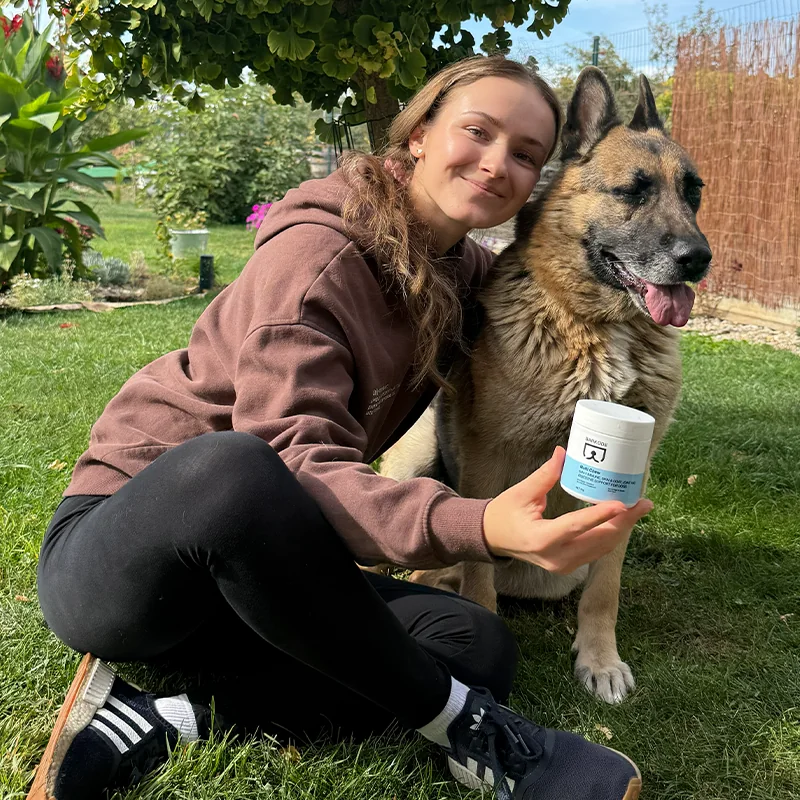 Stăpână stând în grădină cu ciobănescul ei german și un borcan de Multi Chew